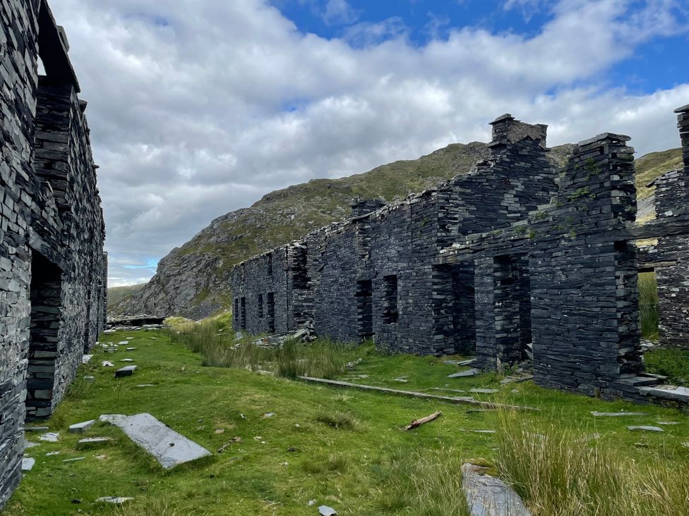 Ruins of a slate building surrounded by grass and mountains at Tafarn Trip in Tan Y Bwlch, Maentwrog