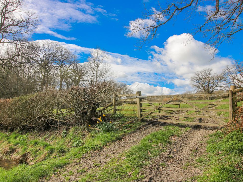 A wooden gate at the end of a path surrounded by trees at Trooper's Barn in Westhope