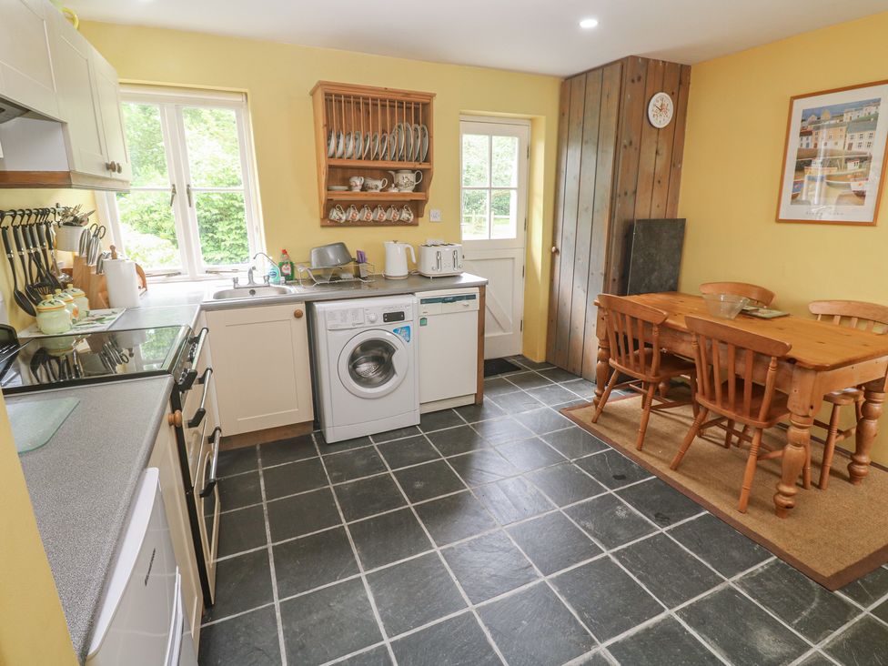 A kitchen with a washing machine and dining table at Swallows St Keverne, Lizard Peninsula