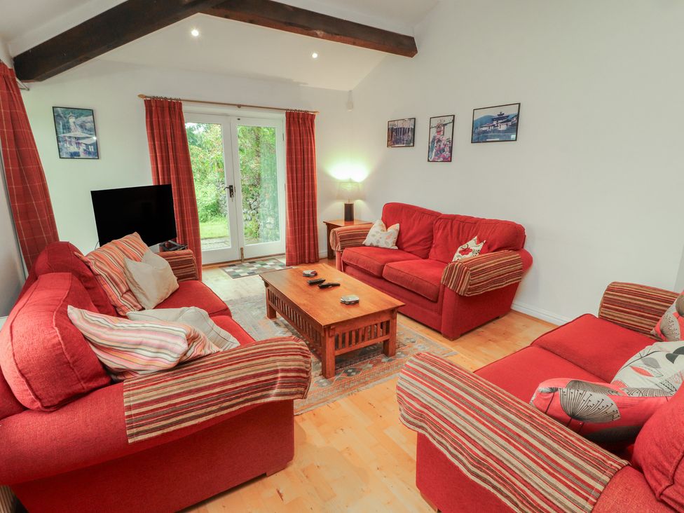 A living room with red sofas and a coffee table at Winster Fields in Cartmel Fell near Windermere