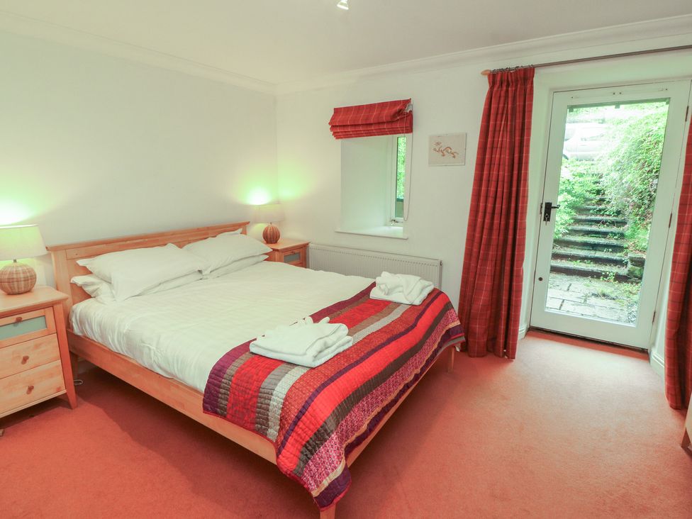 A bedroom with a bed and sliding door at Winster Fields Cartmel Fell near Windermere