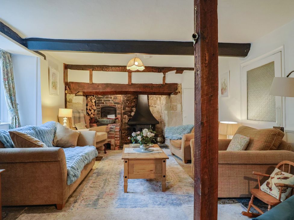 A living room with sofas, a coffee table, and a fireplace at Church Farmhouse in Winsham