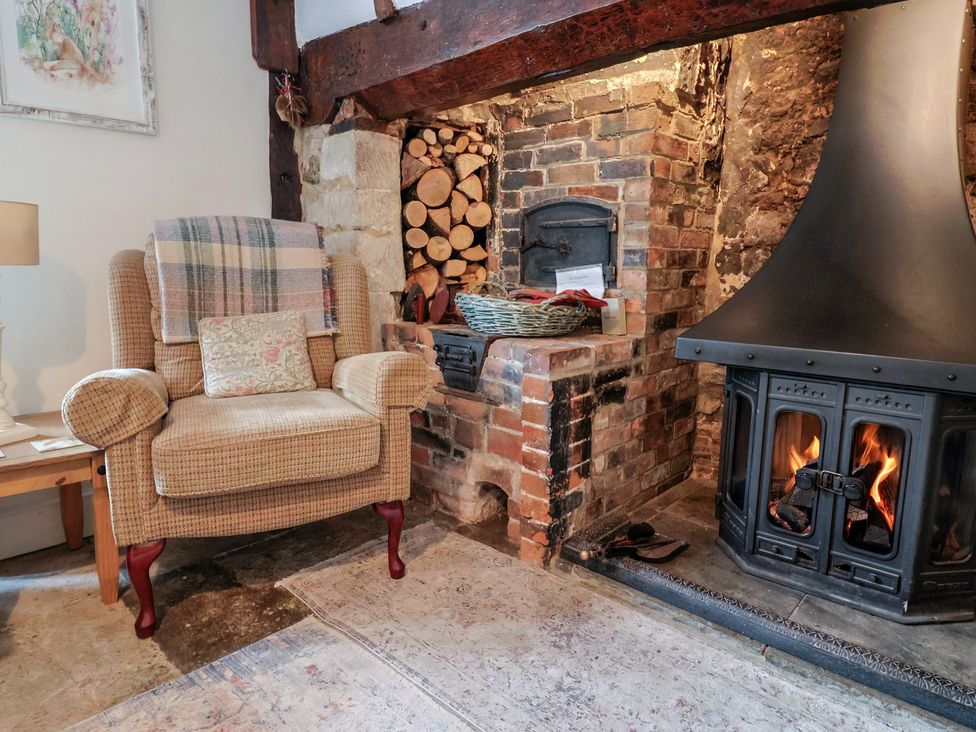 A living room with an armchair and fireplace at Church Farmhouse in Winsham