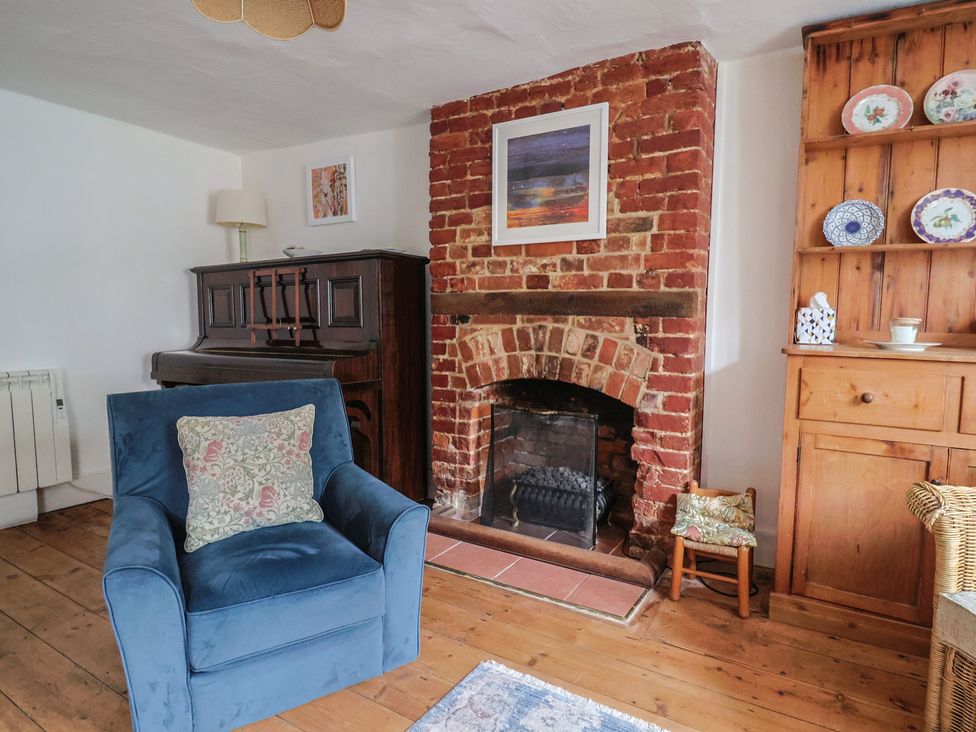 A living room with a fireplace and piano at Church Farmhouse in Winsham