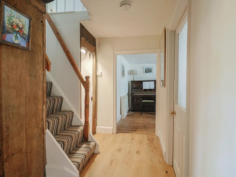 A hallway with a staircase and piano at Church Farmhouse in Winsham
