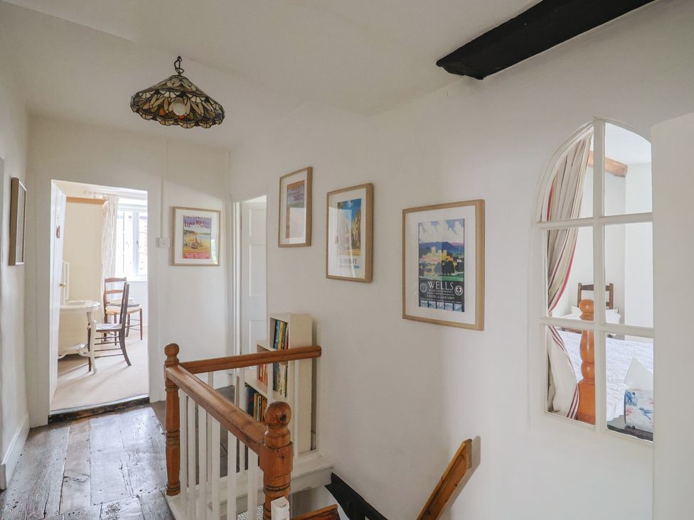 A hallway with a staircase and pictures on the wall at Church Farmhouse in Winsham