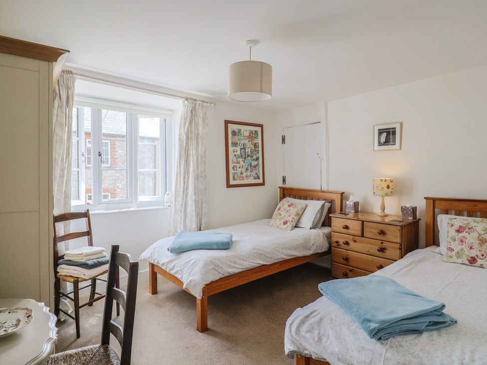 A bedroom with two beds and a chair at Church Farmhouse in Winsham
