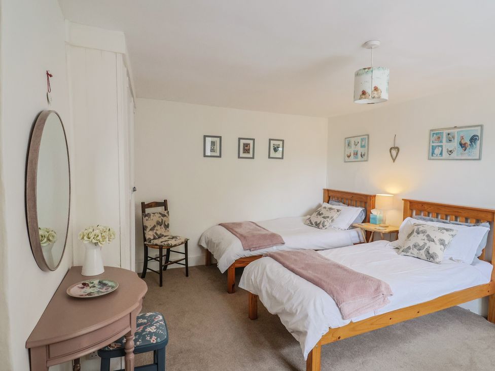 A bedroom with two beds and a chair at Church Farmhouse in Winsham
