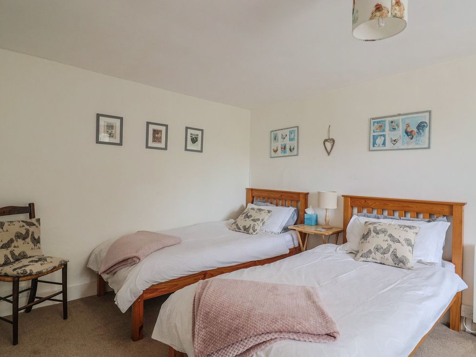 A bedroom with two beds and a chair at Church Farmhouse in Winsham