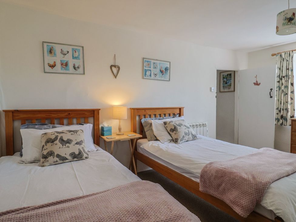A bedroom with two beds and bedside table at Church Farmhouse in Winsham