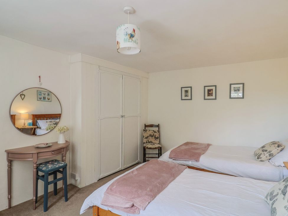 A bedroom with two beds and a table with a mirror at Church Farmhouse in Winsham