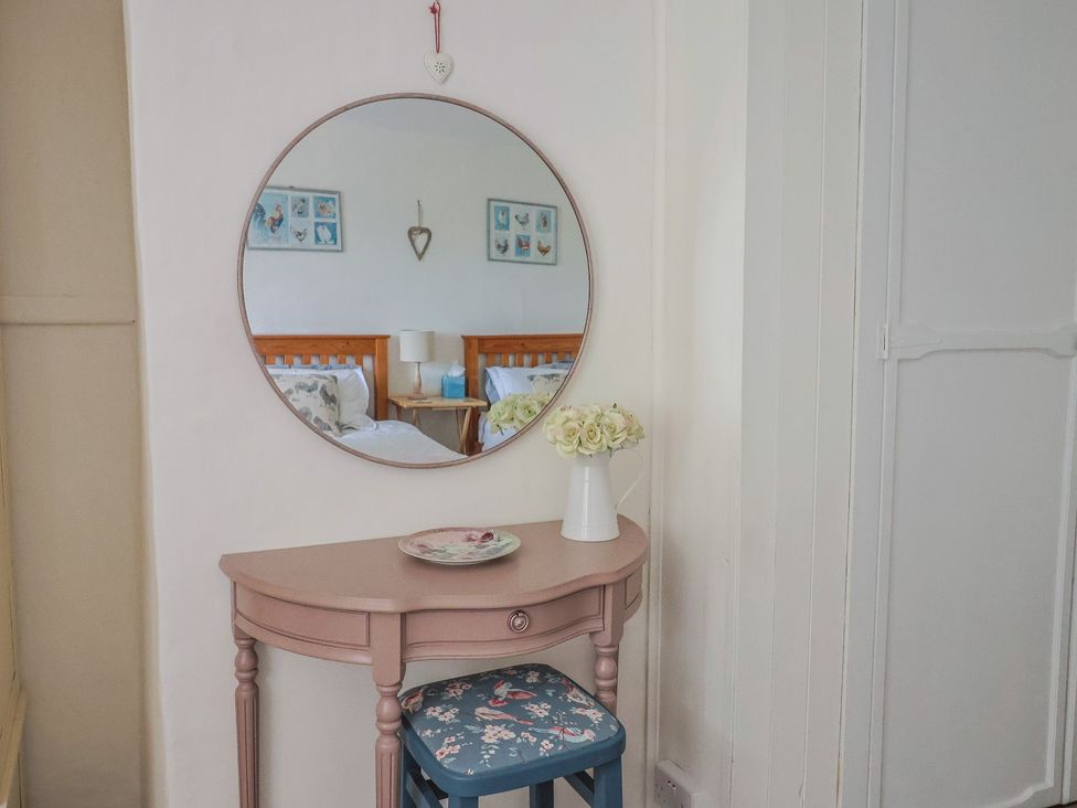 A bedroom corner with a table, chair, and mirror at Church Farmhouse in Winsham