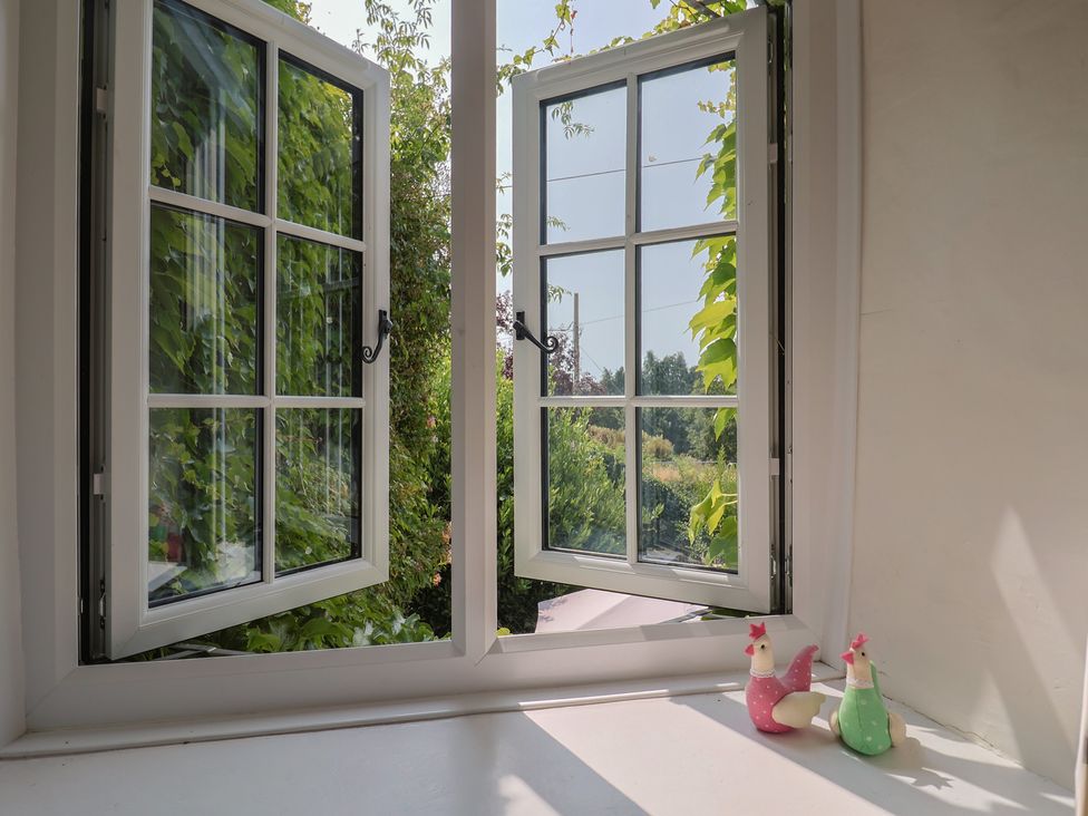 A window with open panes and painted chickens on the sill at Church Farmhouse in Winsham