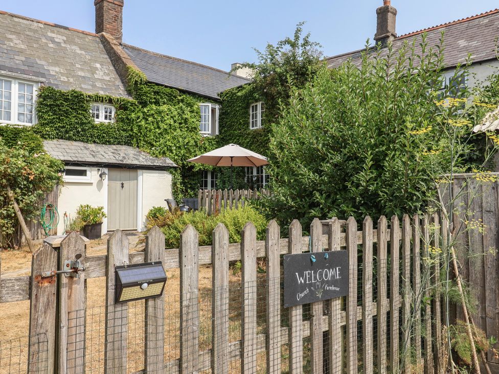 An outdoor view of a house with a welcome sign and fencing at Church Farmhouse Winsham