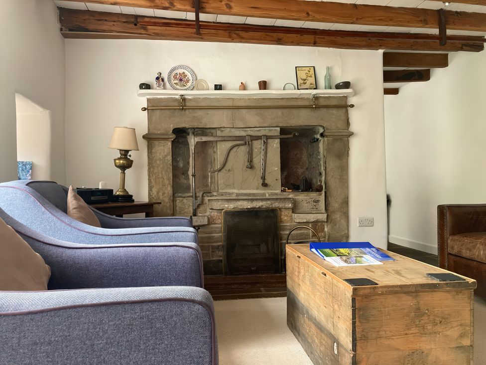 A living room with a fireplace and coffee table at The Old Post Office in Marrick near Reeth