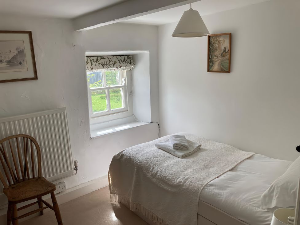 A bedroom with a bed, chair, window, and radiator at The Old Post Office in Marrick near Reeth