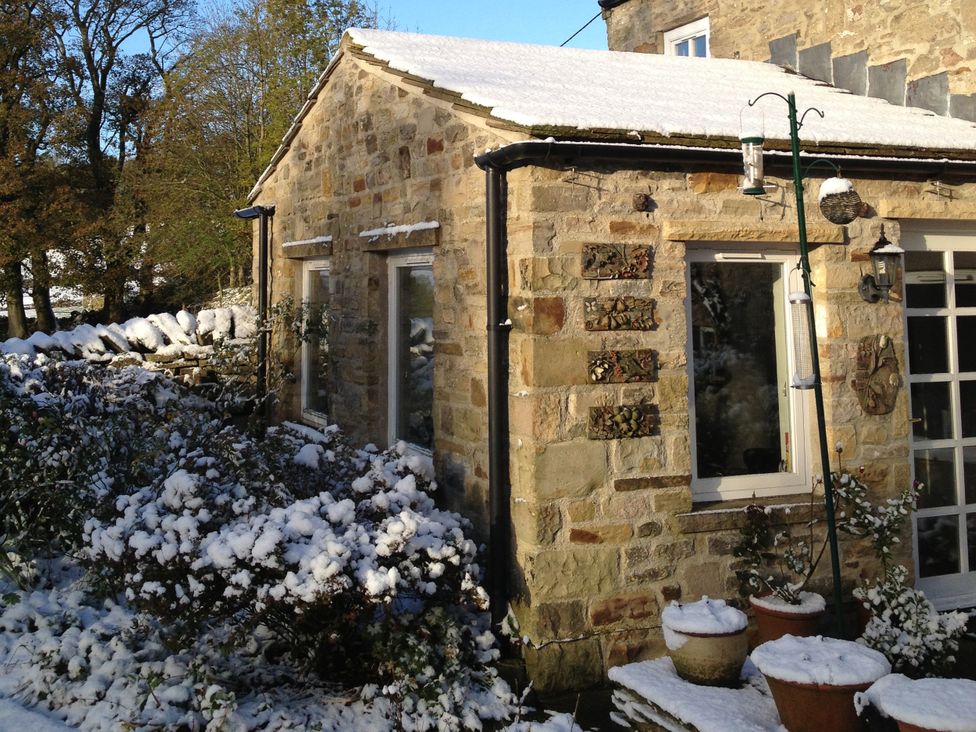 An outdoor view of a cottage with snow on the roof at The Old Post Office in Marrick near Reeth