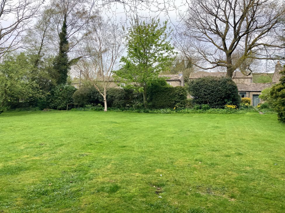 A garden with grass and trees at The Old Post Office in Marrick near Reeth