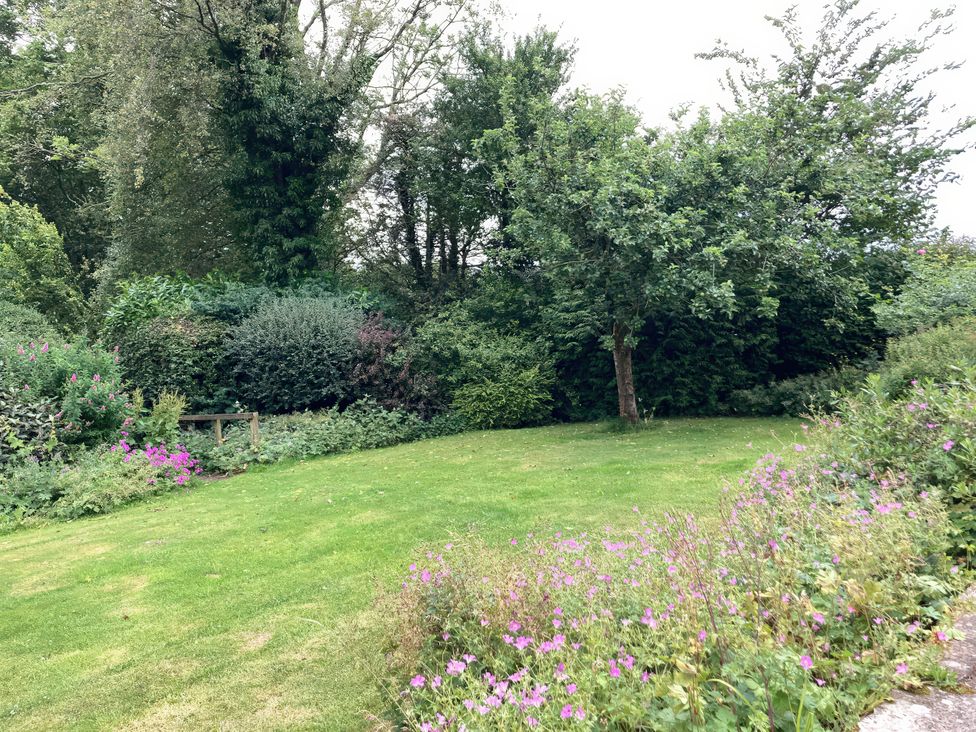 A garden with grass, trees, and flowers at The Old Post Office in Marrick near Reeth