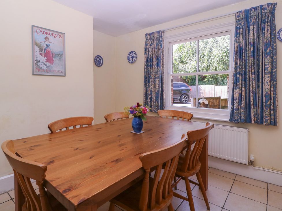 A dining room with a wooden table and flowers at The Lock House in Gloucester