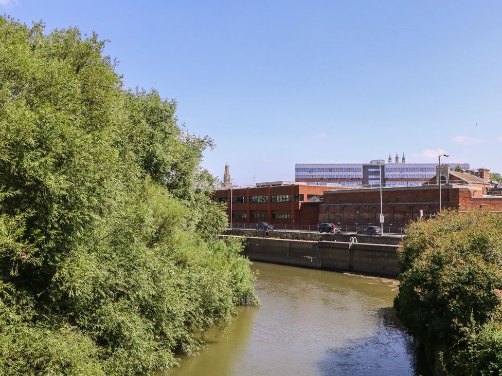 A view of buildings and trees alongside a river at The Lock House in Gloucester