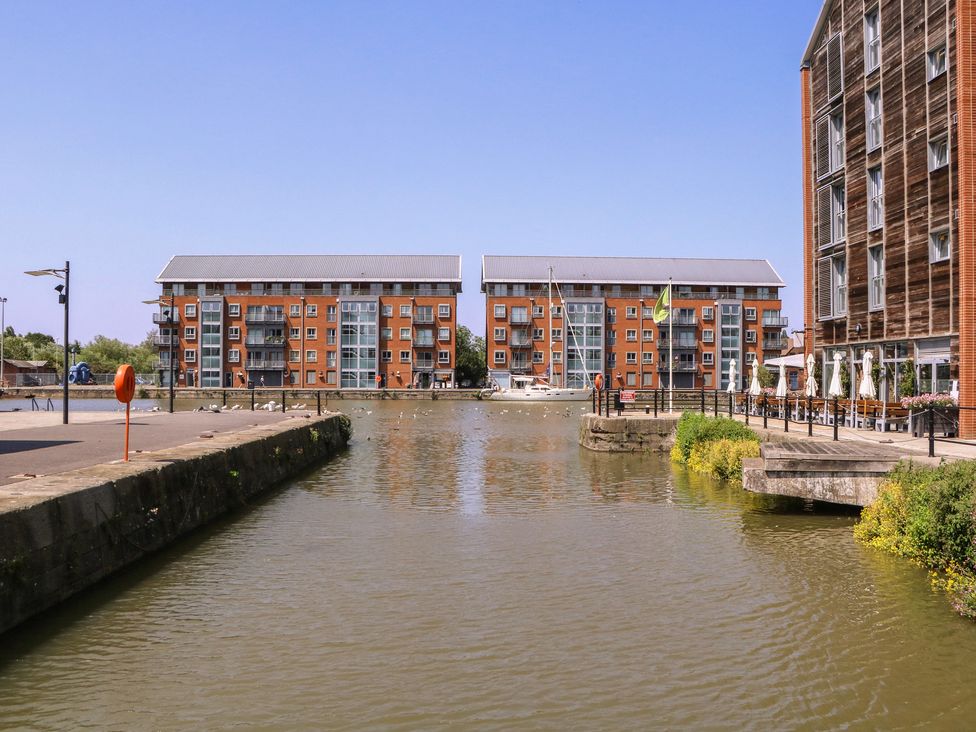 A waterfront view of buildings and a boat at The Lock House in Gloucester