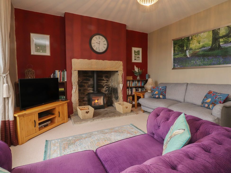 A living room with a fireplace and sofa at Canalside Cottage in Farnhill near Skipton