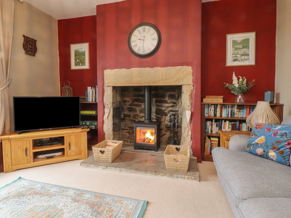 A living room with a fireplace and television at Canalside Cottage in Farnhill near Skipton