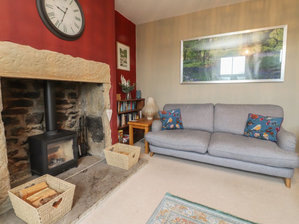 A living room with a fireplace, a sofa and a bookshelf at Canalside Cottage Farnhill near Skipton