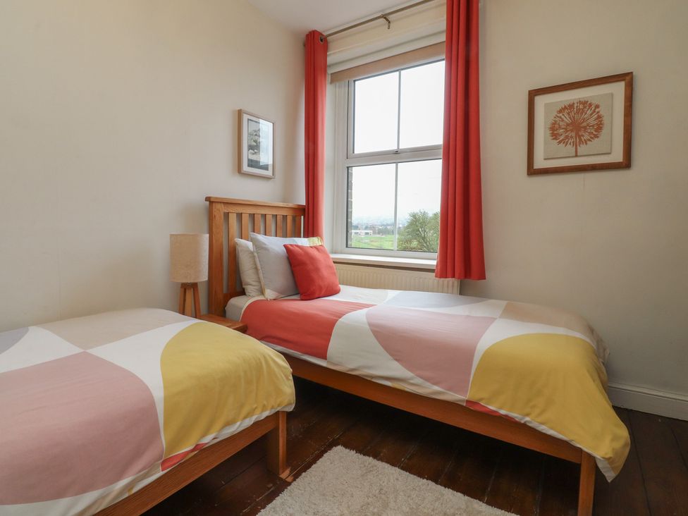 A bedroom with two beds and a window at Canalside Cottage in Farnhill near Skipton