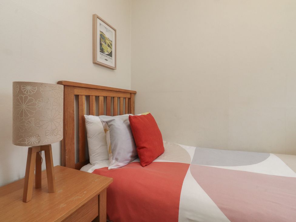 A bedroom with a bed, lamp, and picture frame at Canalside Cottage in Farnhill near Skipton