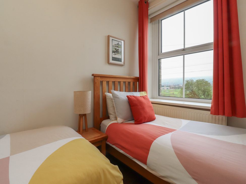 A bedroom with two beds and a window at Canalside Cottage in Farnhill near Skipton