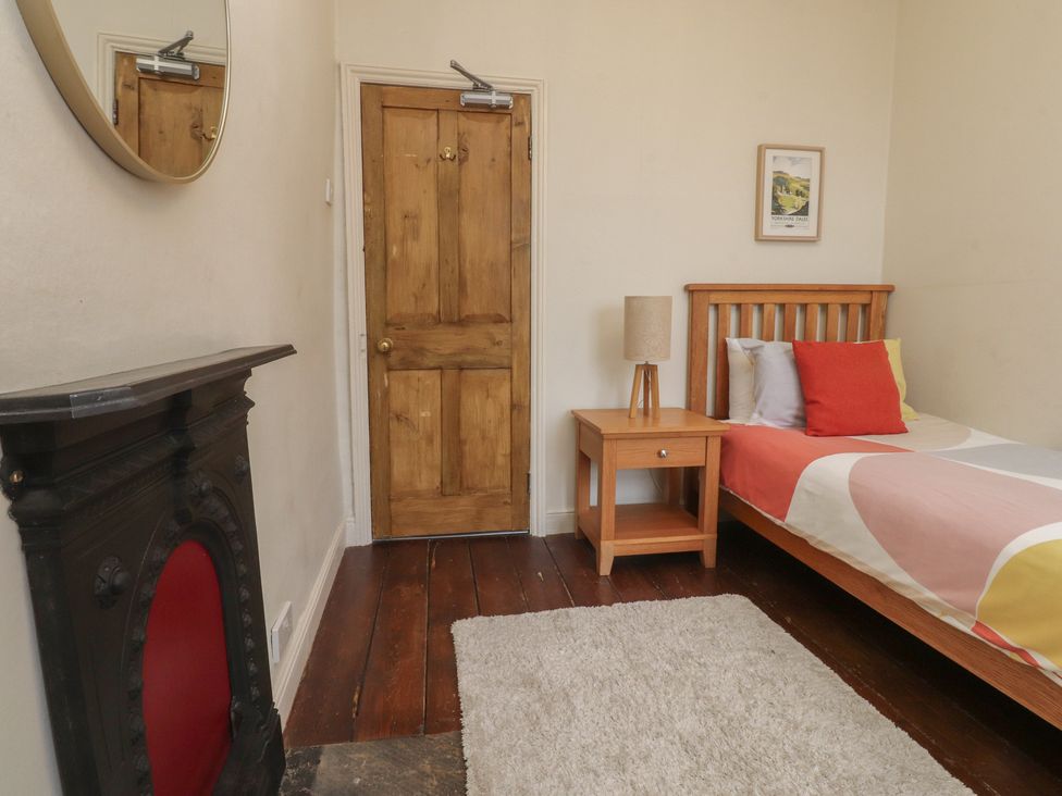 A bedroom with a bed, nightstand, and door at Canalside Cottage in Farnhill near Skipton