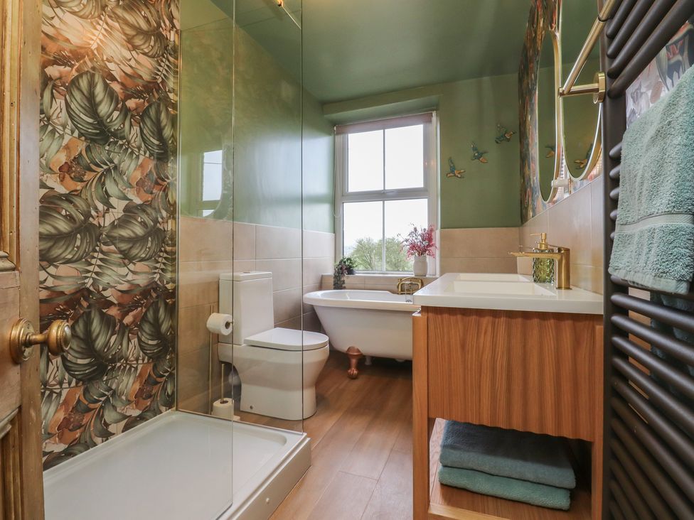 A bathroom with a shower, toilet, bathtub, and sink at Canalside Cottage in Farnhill near Skipton
