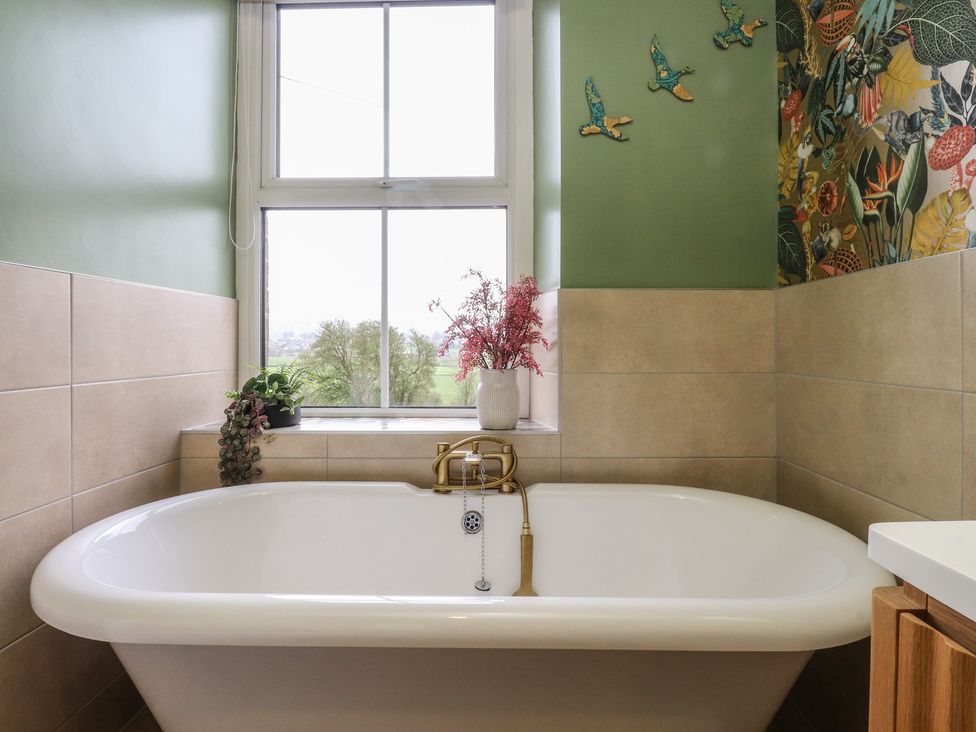 A bathroom with a bathtub and window at Canalside Cottage in Farnhill near Skipton