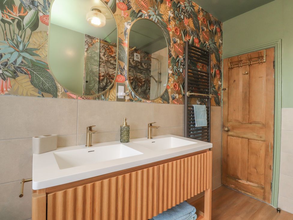 A bathroom with a double sink and mirrors at Canalside Cottage in Farnhill near Skipton