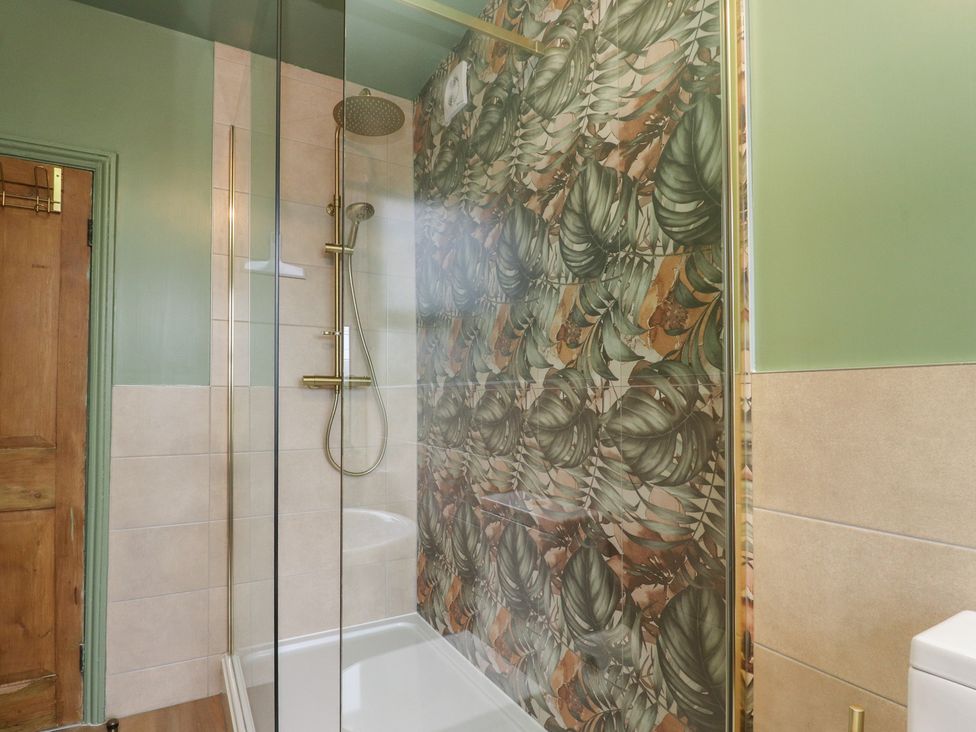 A bathroom with a shower and tiles at Canalside Cottage in Farnhill near Skipton