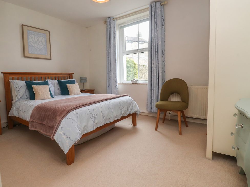 A bedroom with a bed and chair at Canalside Cottage in Farnhill near Skipton