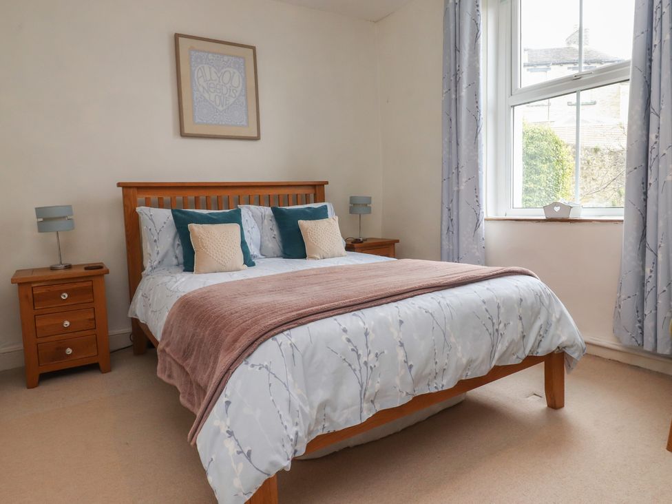 A bedroom with a bed and nightstand at Canalside Cottage in Farnhill near Skipton