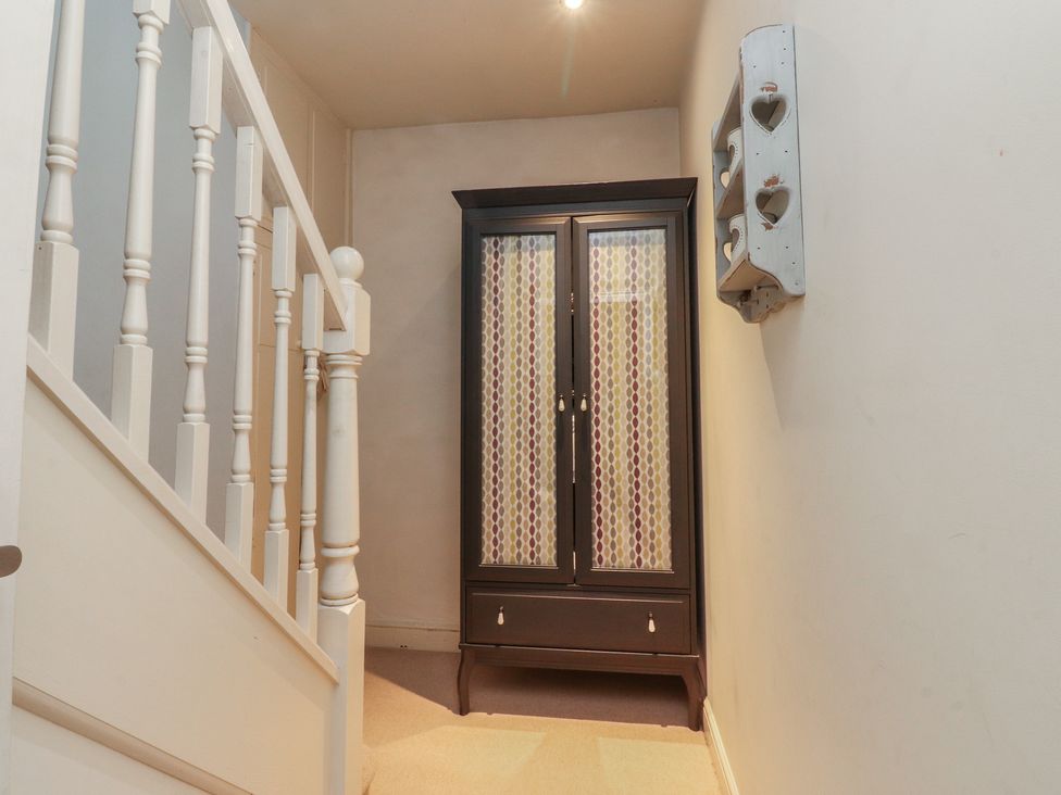 A hallway with a cupboard and stairs at Canalside Cottage in Farnhill near Skipton