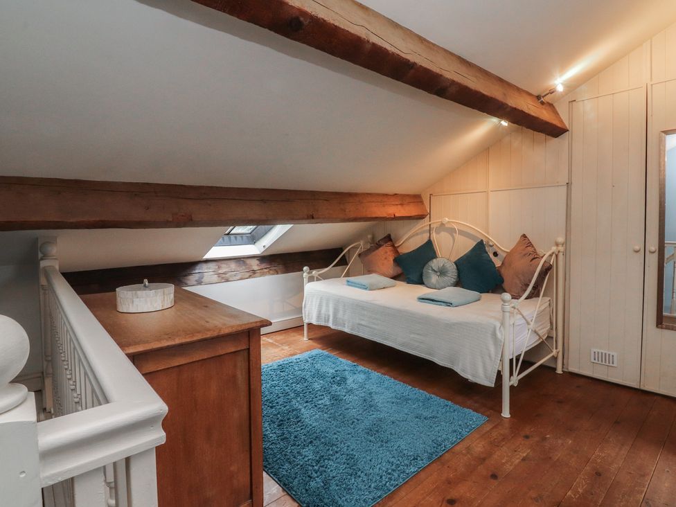 A bedroom with a bed, wardrobe, and wooden flooring at Canalside Cottage in Farnhill near Skipton