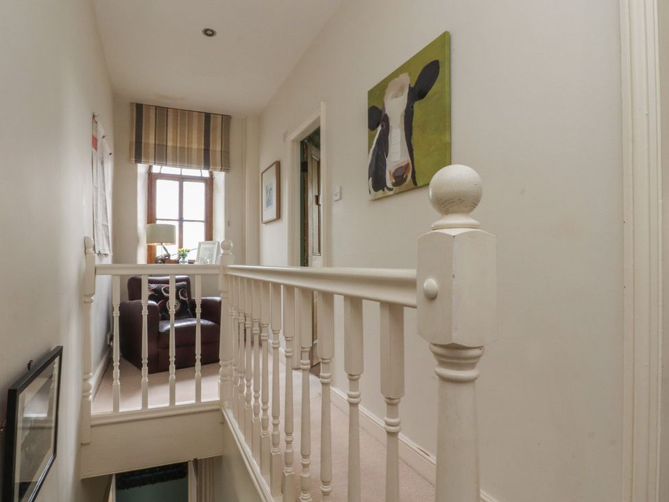 A hallway with a staircase and a chair at Canalside Cottage Farnhill near Skipton