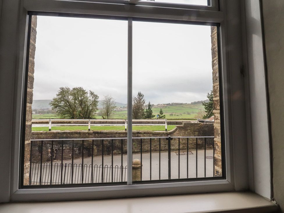 A view of trees and a hill from a window at Canalside Cottage in Farnhill near Skipton