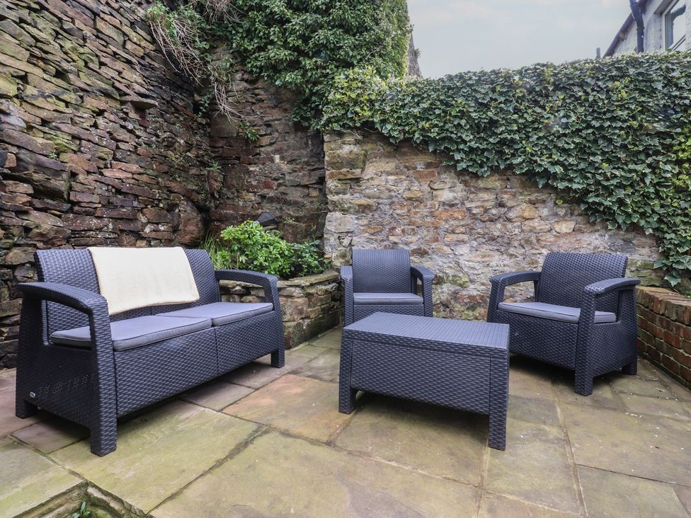 An outdoor seating area with sofa, chairs, and table at Canalside Cottage Farnhill near Skipton