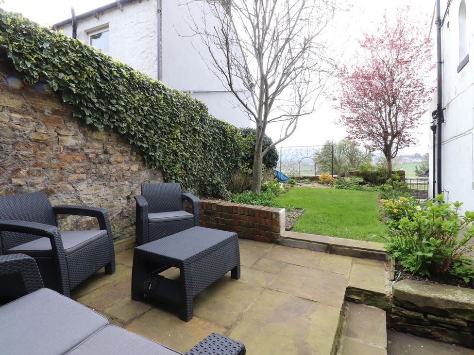 A garden with seating area and flowerbed at Canalside Cottage in Farnhill near Skipton
