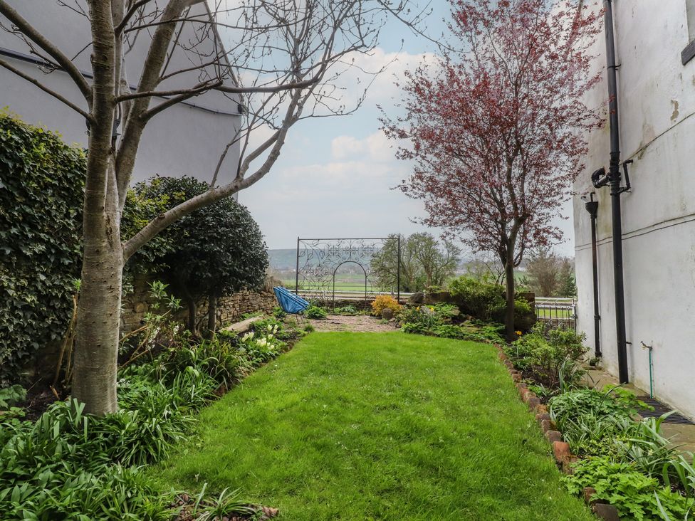 A garden with a swing and trees at Canalside Cottage in Farnhill near Skipton