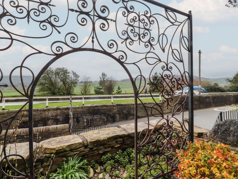 A wrought iron gate overlooking a garden and road at Canalside Cottage in Farnhill near Skipton