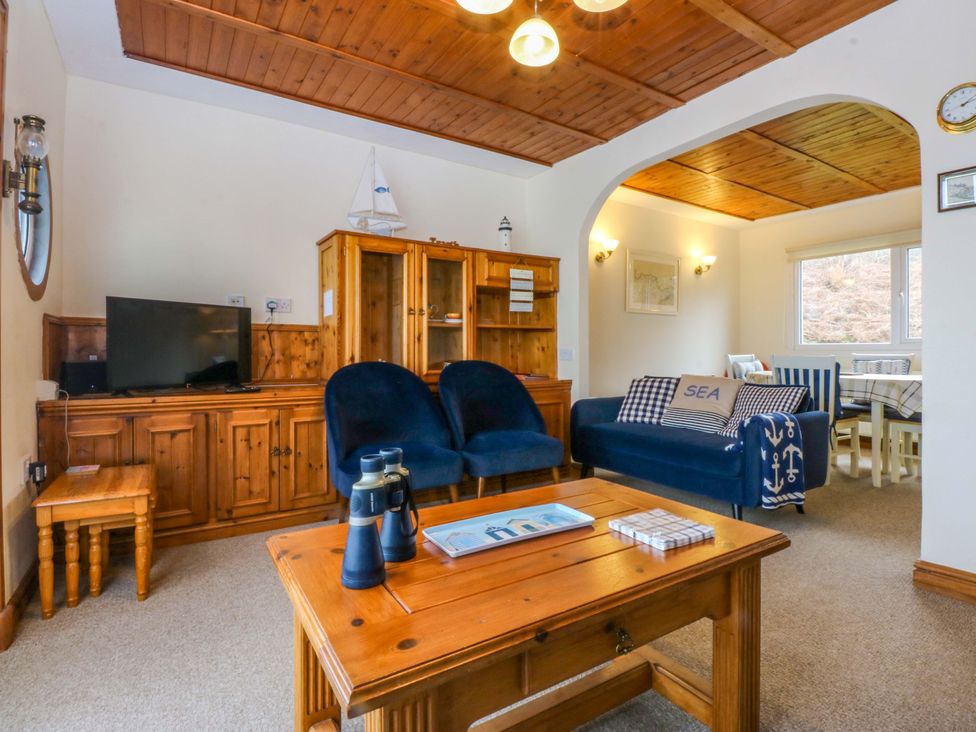 A living room with a television, sofa, and coffee table at Min Y Traeth in Bull Bay