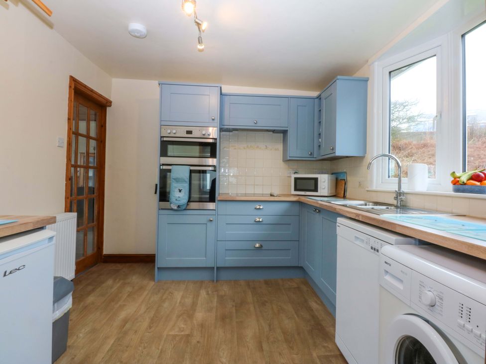 A kitchen with appliances and cabinets at Min Y Traeth in Bull Bay