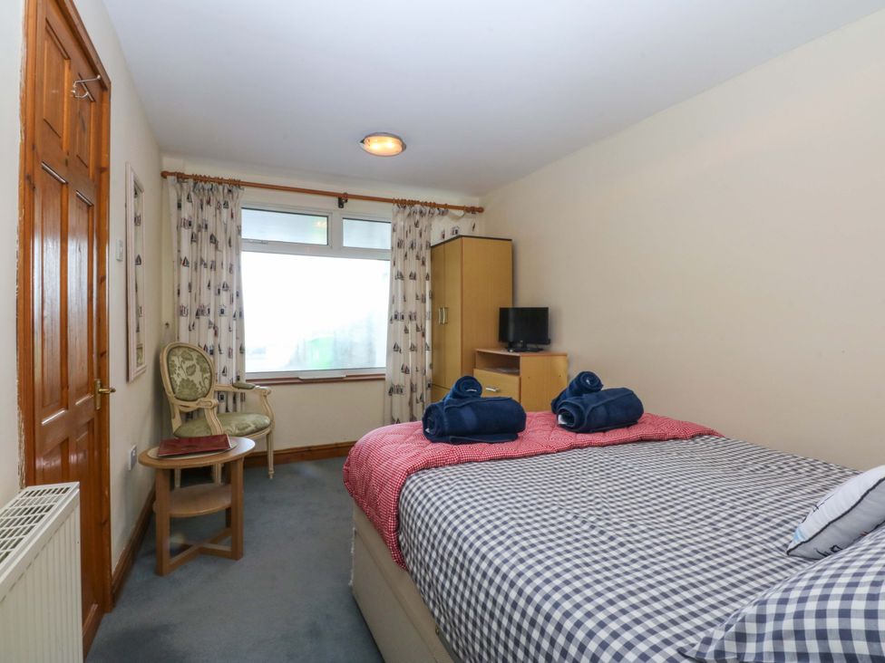 A bedroom with a bed and television at Min Y Traeth in Bull Bay